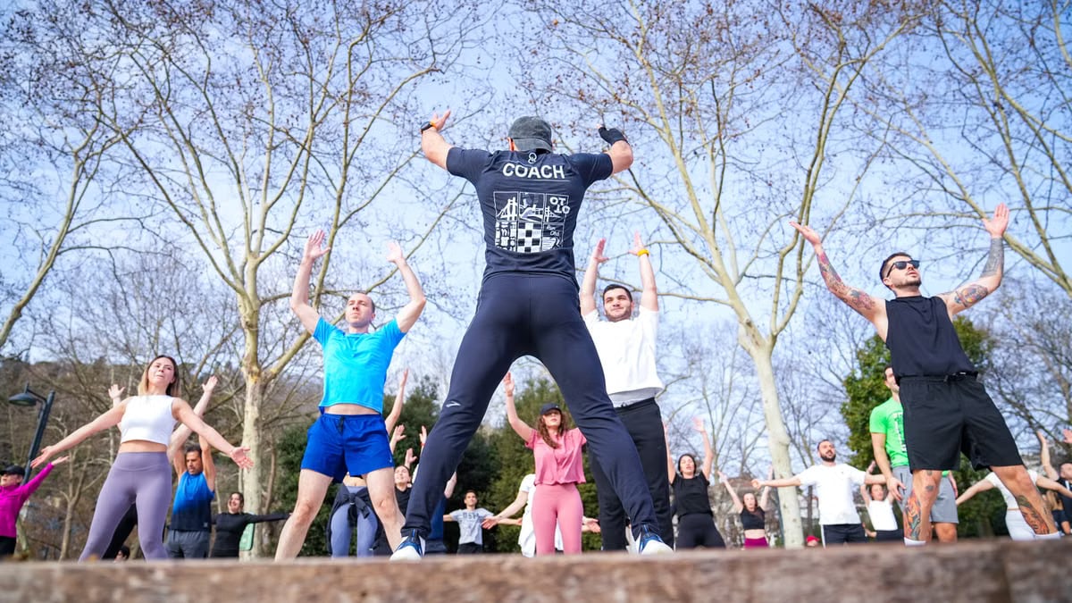Group exercise session in a sunny Istanbul park led by a fitness coach outdoors.